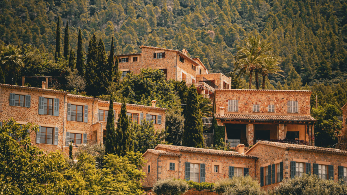 Malersicher Blick auf Deià, Mallorca, mit rustikalen Steinhäusern, die in üppigem Grün und Bergen eingebettet sind.