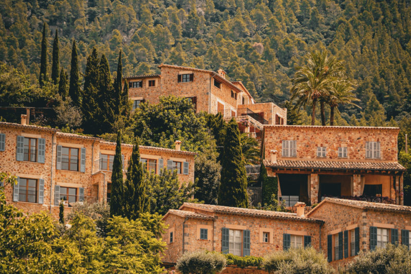 Malersicher Blick auf Deià, Mallorca, mit rustikalen Steinhäusern, die in üppigem Grün und Bergen eingebettet sind.